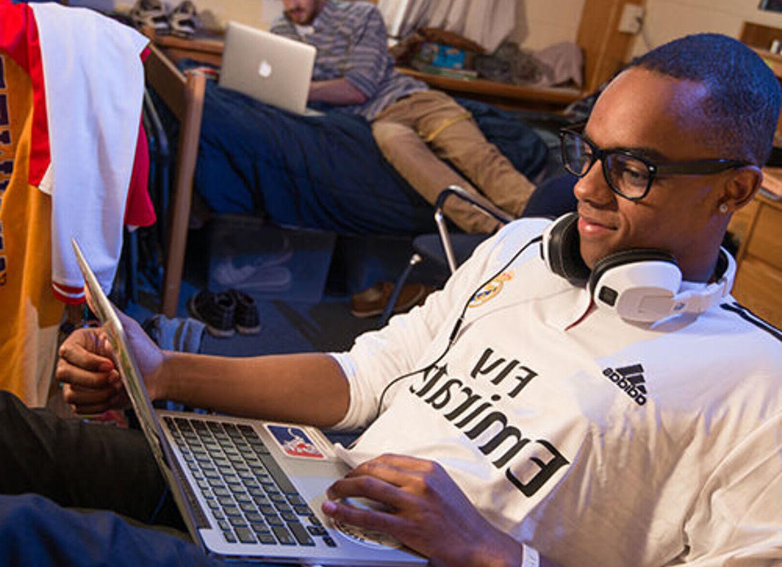 A student works on a laptop in a dorm room