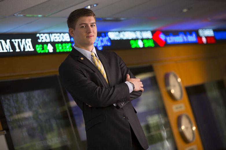 A student in a suit poses in the finance trading room